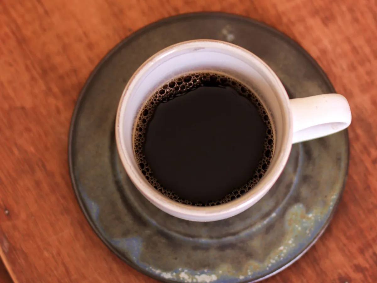 Black coffee in a light cup on a ceramic saucer