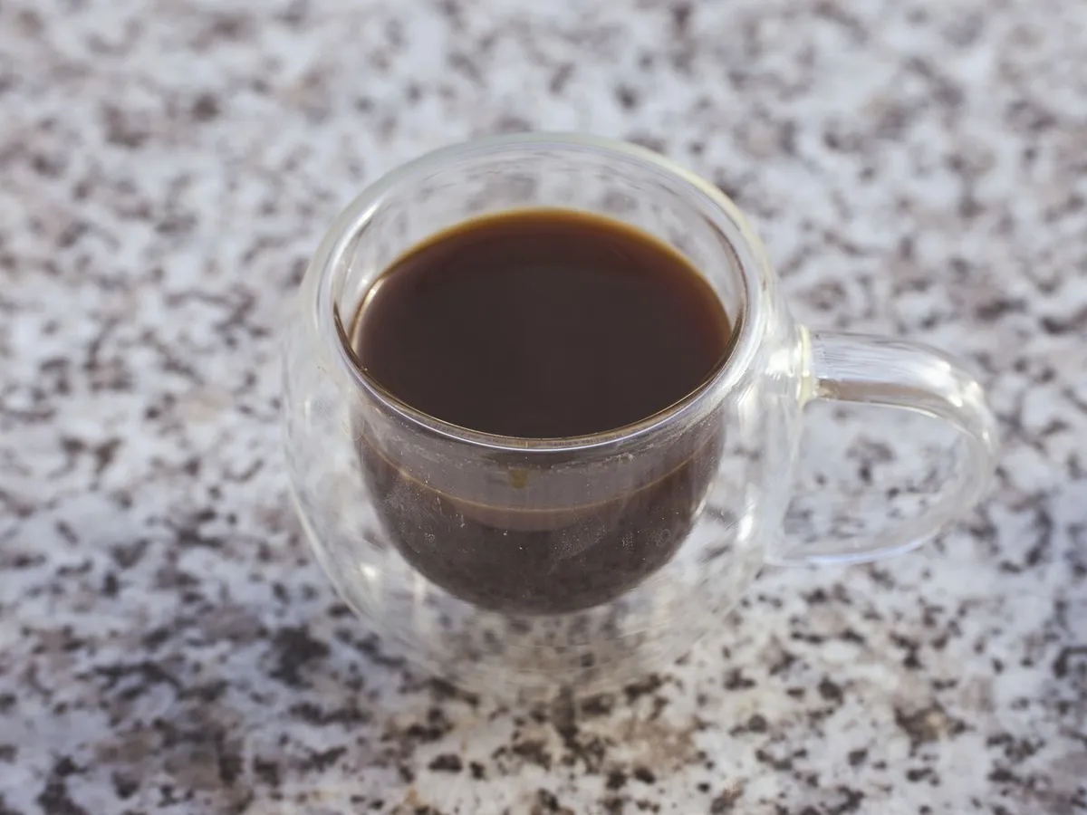 御影石の上のガラスのマグカップに入ったブラックコーヒー