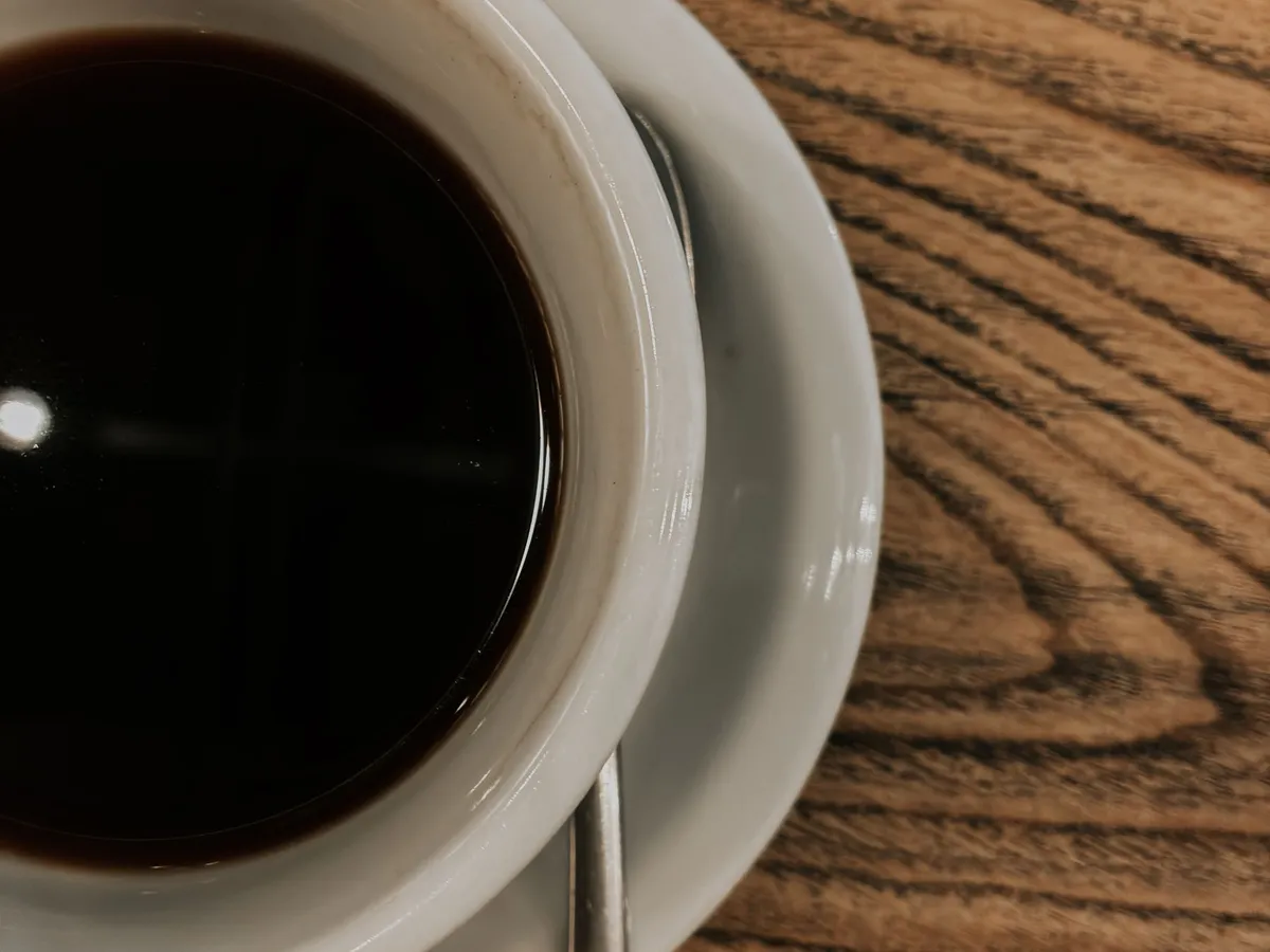 Close-up of black coffee in a white cup with a spoon