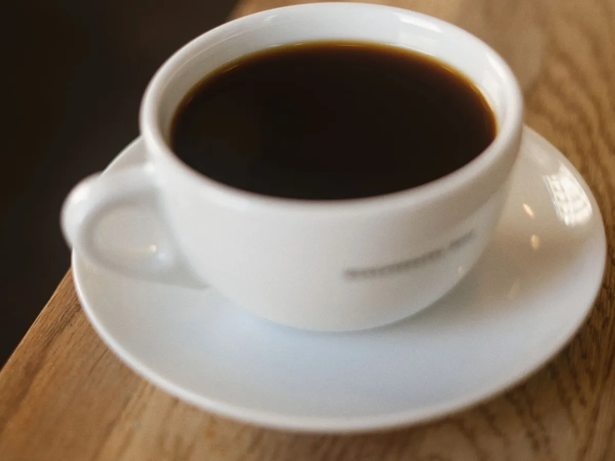 White cup of black coffee on a saucer on the table