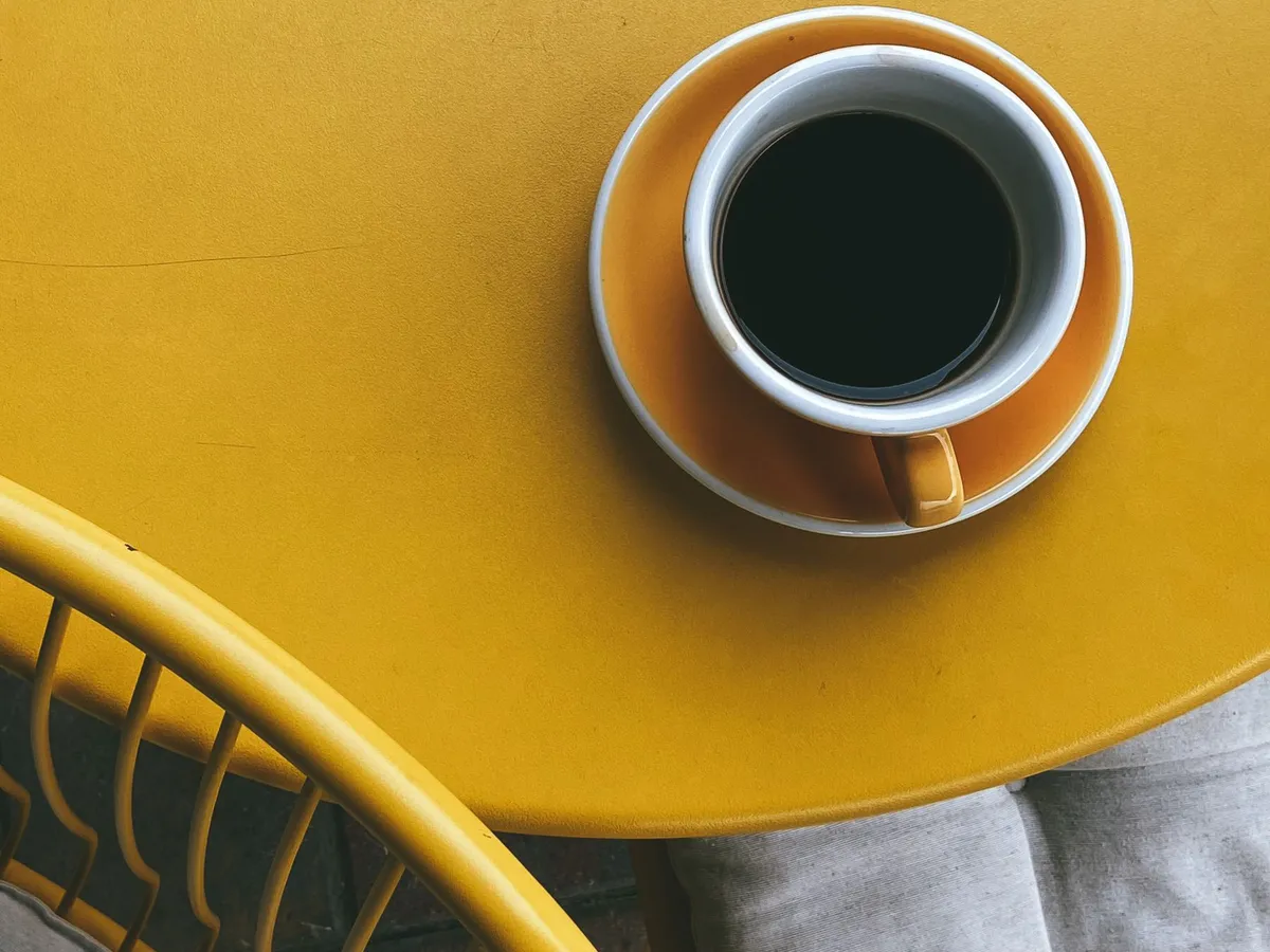 Black coffee in a yellow cup, seen from above