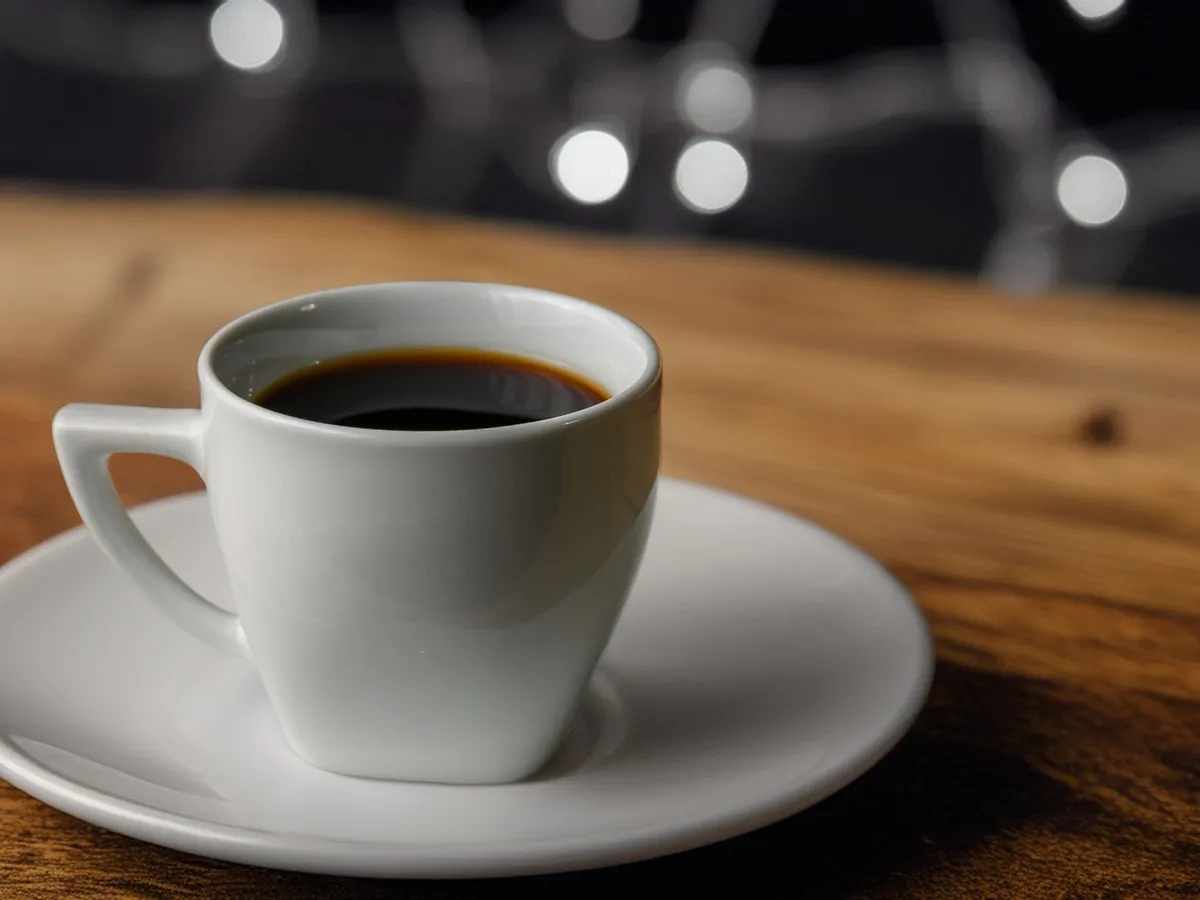 Black coffee in a white cup and saucer with a blurred background